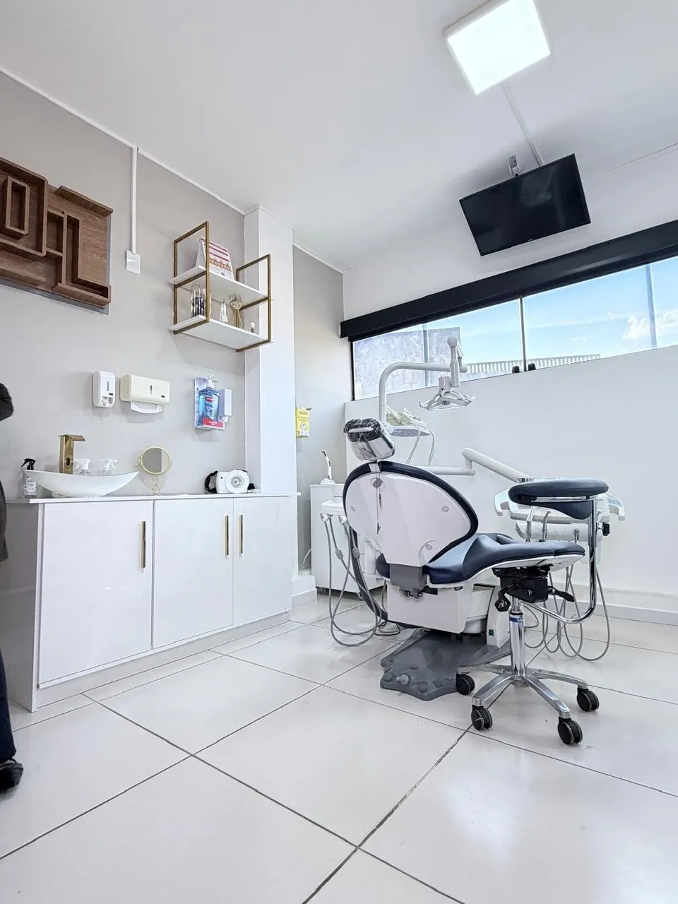Sala de atendimento do consultório, com a cadeira odontológica e a bancada de apoio